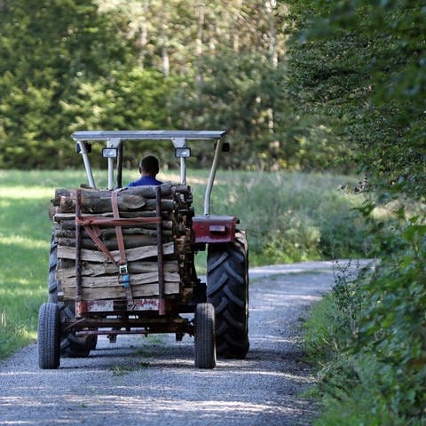 Ein Bauer fährt mit einem Traktor auf einem Feldweg | Wer darf mit dem Auto auf Feldwegen fahren?