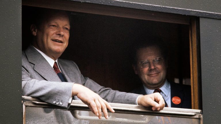 Willy Brandt und Günter Guillaume stehen an einem geöffneten Fenster im Zug